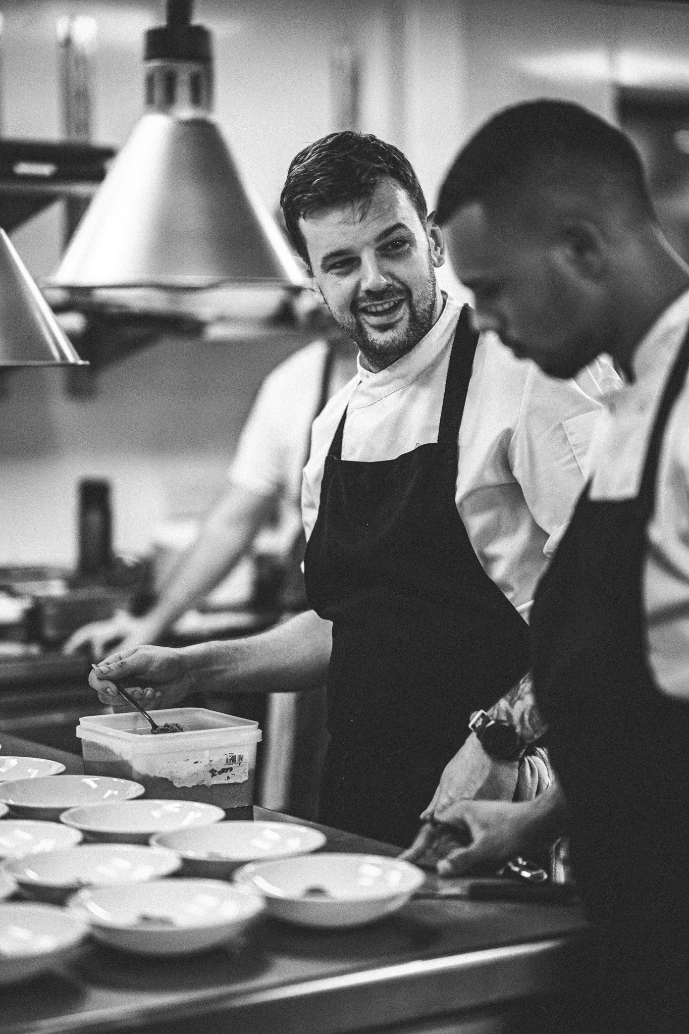 Black and white candid photograph of Fergus Wilford in the kitchen